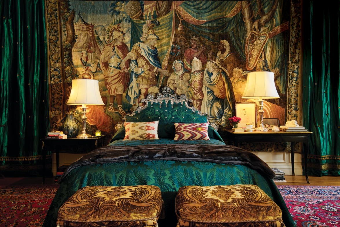 Luxurious bedroom with a decorative tapestry, opulent green bedding, ornate lamps, and intricate furnishings.