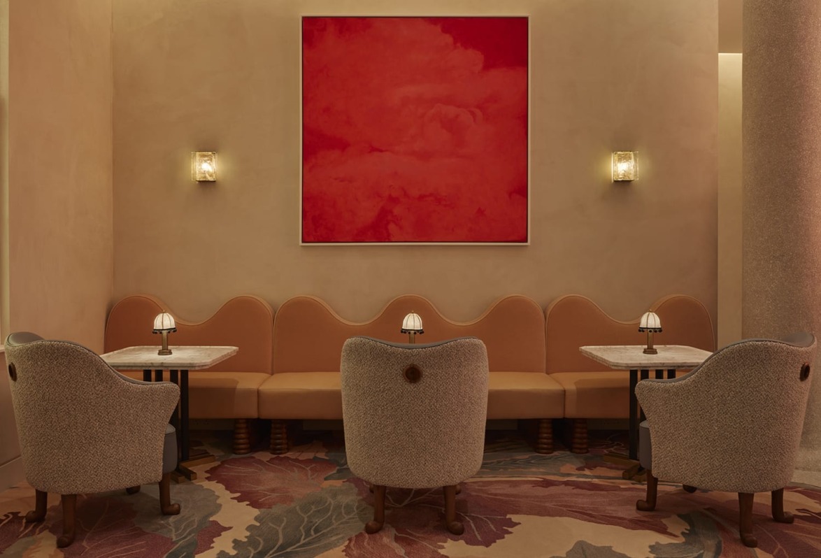 Cozy cafe corner with four armchairs, elegant lighting, and a vibrant red abstract painting on the wall.
