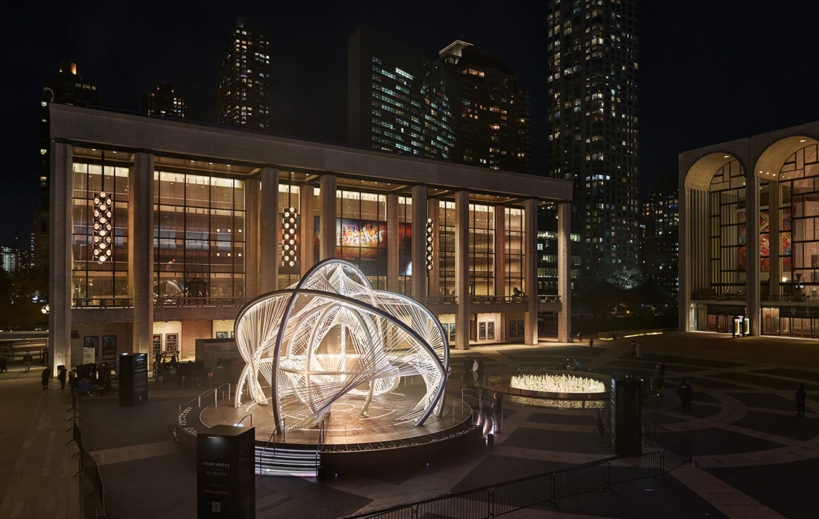 Illuminated outdoor art installation at Lincoln Center Plaza with surrounding skyscrapers at night.