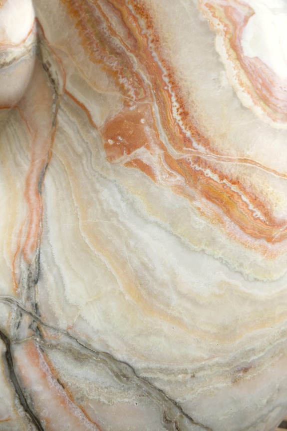 Close-up of a marble surface with swirling patterns of orange, white, and beige.