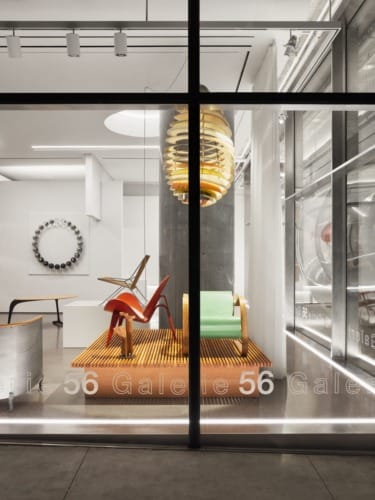 Gallery window display featuring modern chairs and a unique hanging light fixture.