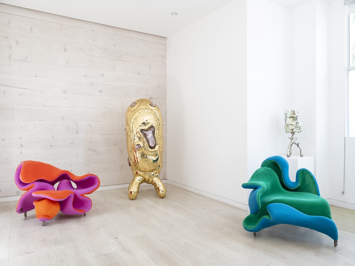 Colorful abstract sculptures in a modern white room with wooden floors and walls.