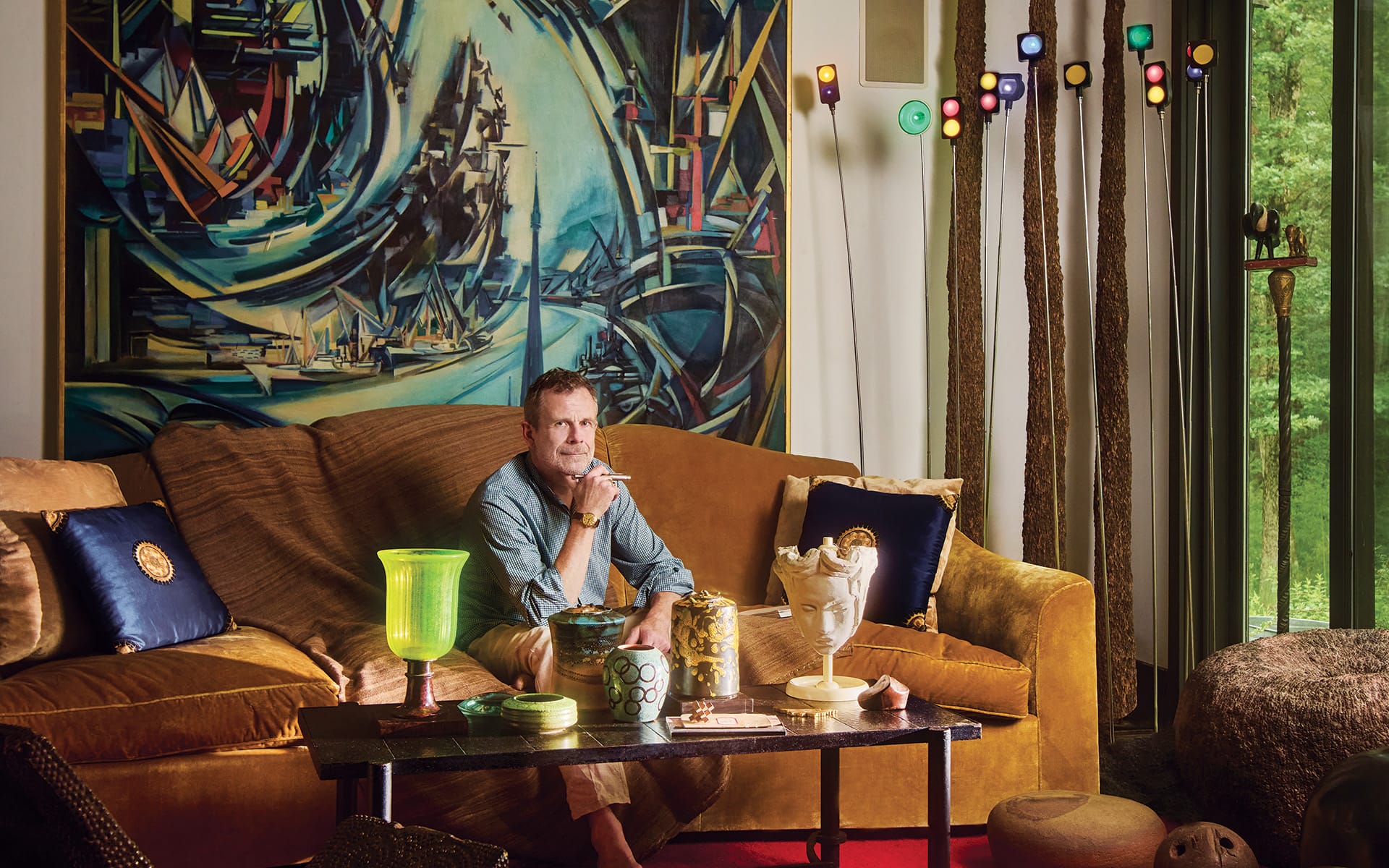At his home in upstate New York, Benoist F. Drut displays an abstract cityscape by Reynold Arnould near a Jacques Adnet cocktail table with an assortment of ceramics.