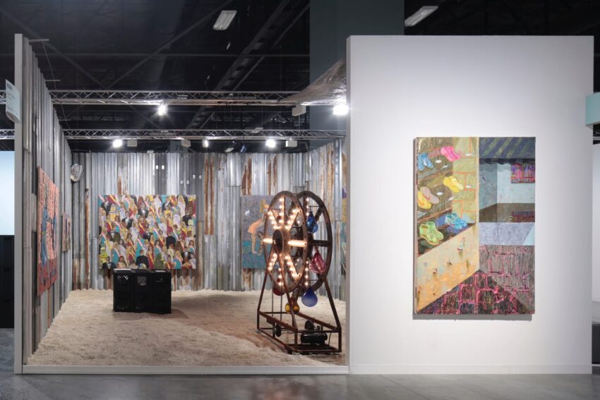 art installation featuring mixed media paintings, a lighted metal structure, and textured flooring in a gallery setting