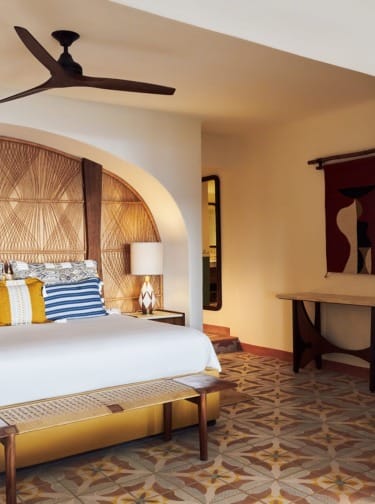 Cozy bedroom with patterned floor, wooden accents, and a ceiling fan, featuring a bed with decorative pillows and a stylish headboard.