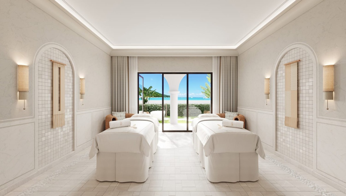 Luxurious spa room with two massage tables, large windows, and an ocean view.