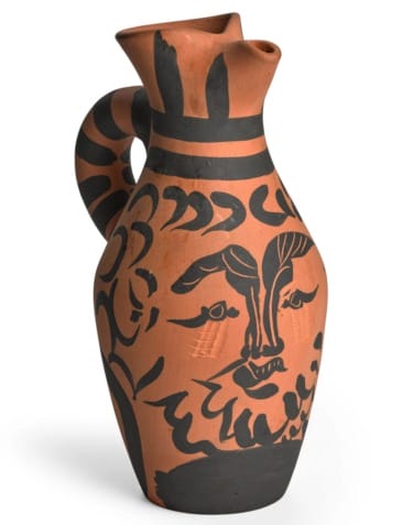 Ceramic jug with black abstract face design and patterns on a terracotta background.