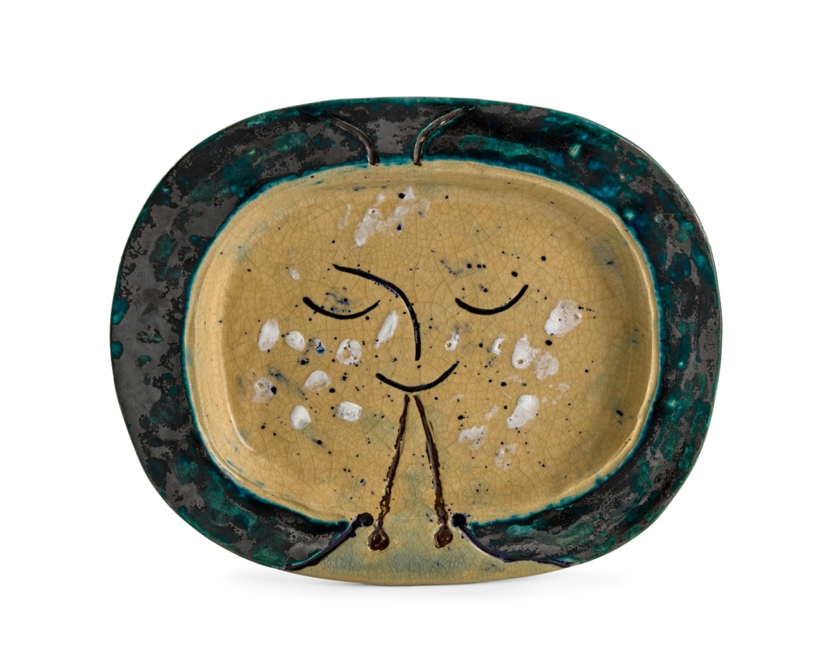 Ceramic plate with abstract face design, featuring a yellow center, dark rim, and green and blue accents.