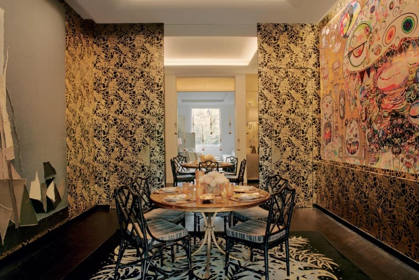 Dining room with patterned wallpaper, an art piece, round table, and chairs on a decorative rug