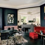 Luxurious living room with dark walls, modern furniture, abstract art, and large mirror reflecting natural light.