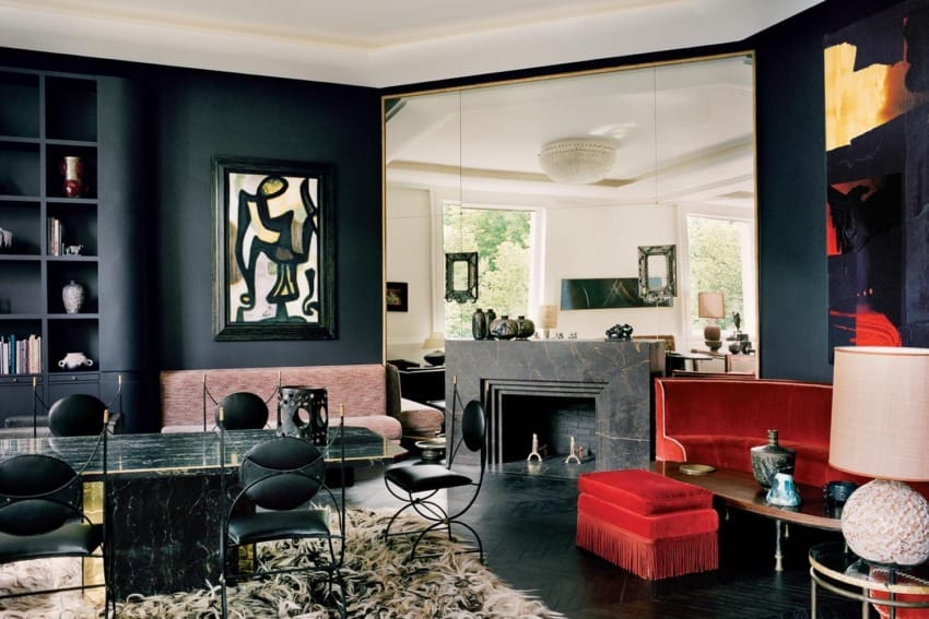 Luxurious living room with dark walls, modern furniture, abstract art, and large mirror reflecting natural light.
