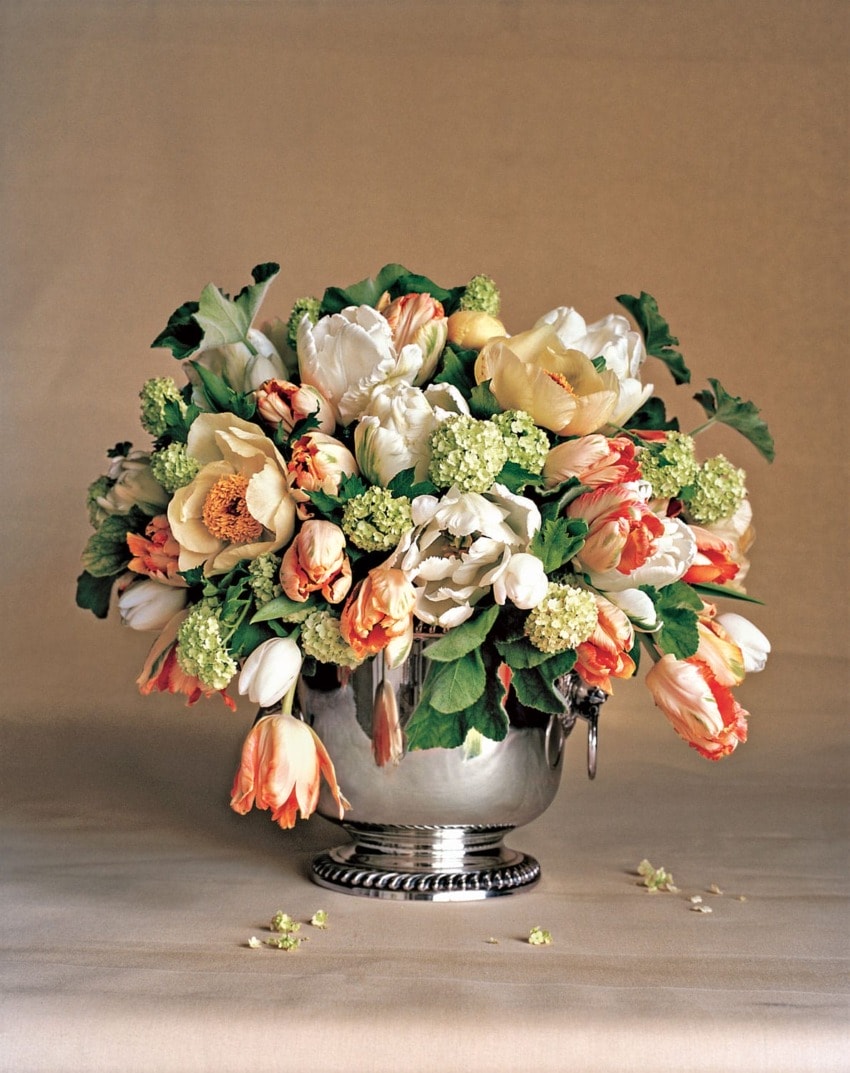Elegant bouquet of tulips and roses in a silver vase against a neutral background.