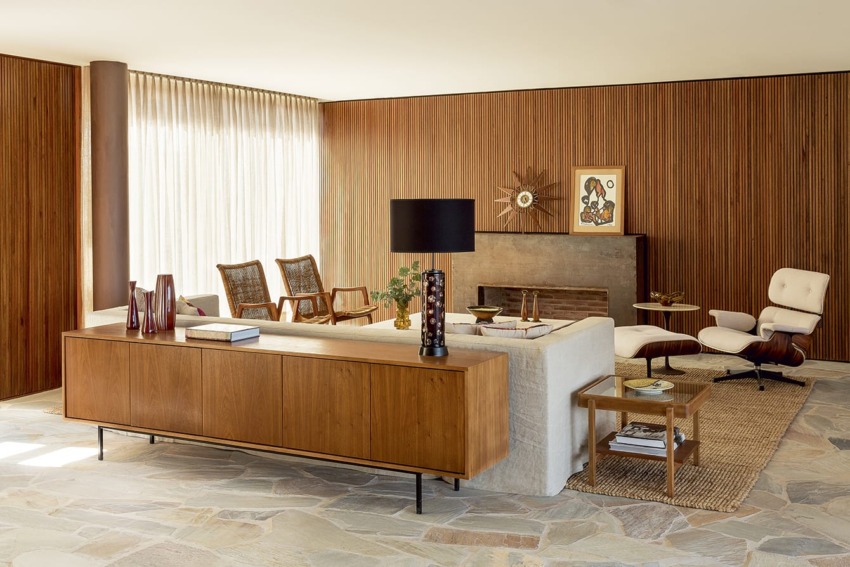 Mid-century modern living room with wood paneling, stylish furniture, art pieces, and a floor lamp creating a cozy atmosphere.