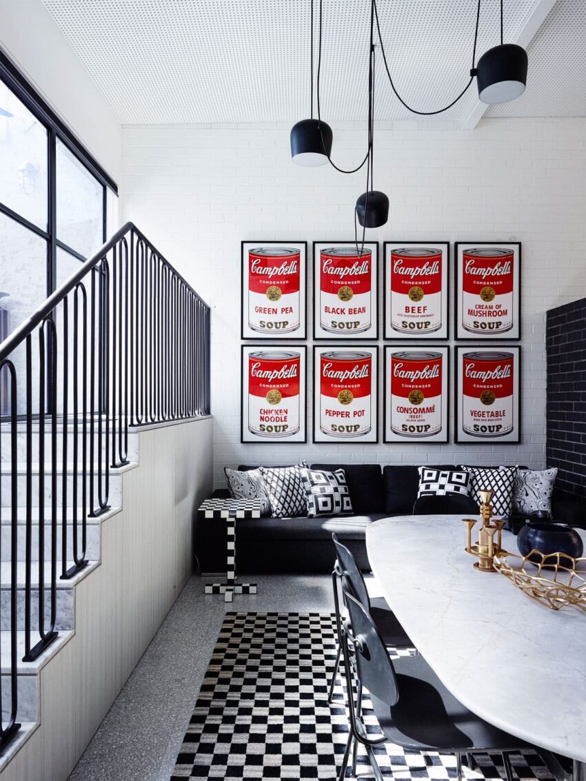 Modern dining area with black and white decor, checkerboard floor, and pop art soup can prints on the wall.