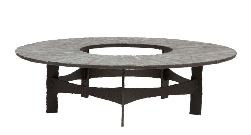 Round stone table with a circular hole in the center and sturdy metal legs.