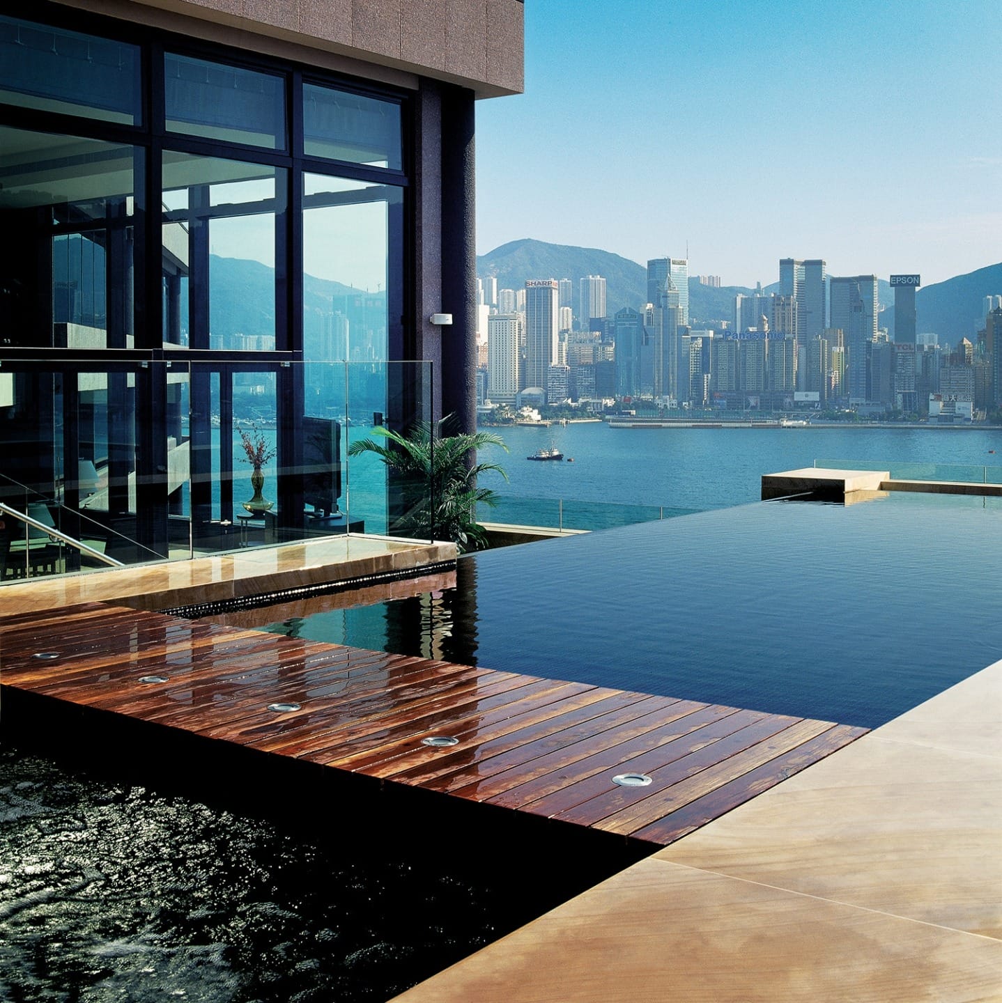 Infinity pool overlooking a city skyline with mountains and a clear blue sky in the background.