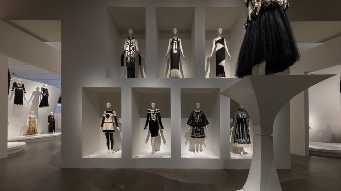 Fashion exhibition showcasing avant-garde black and white dresses on mannequins in a modern gallery setting.