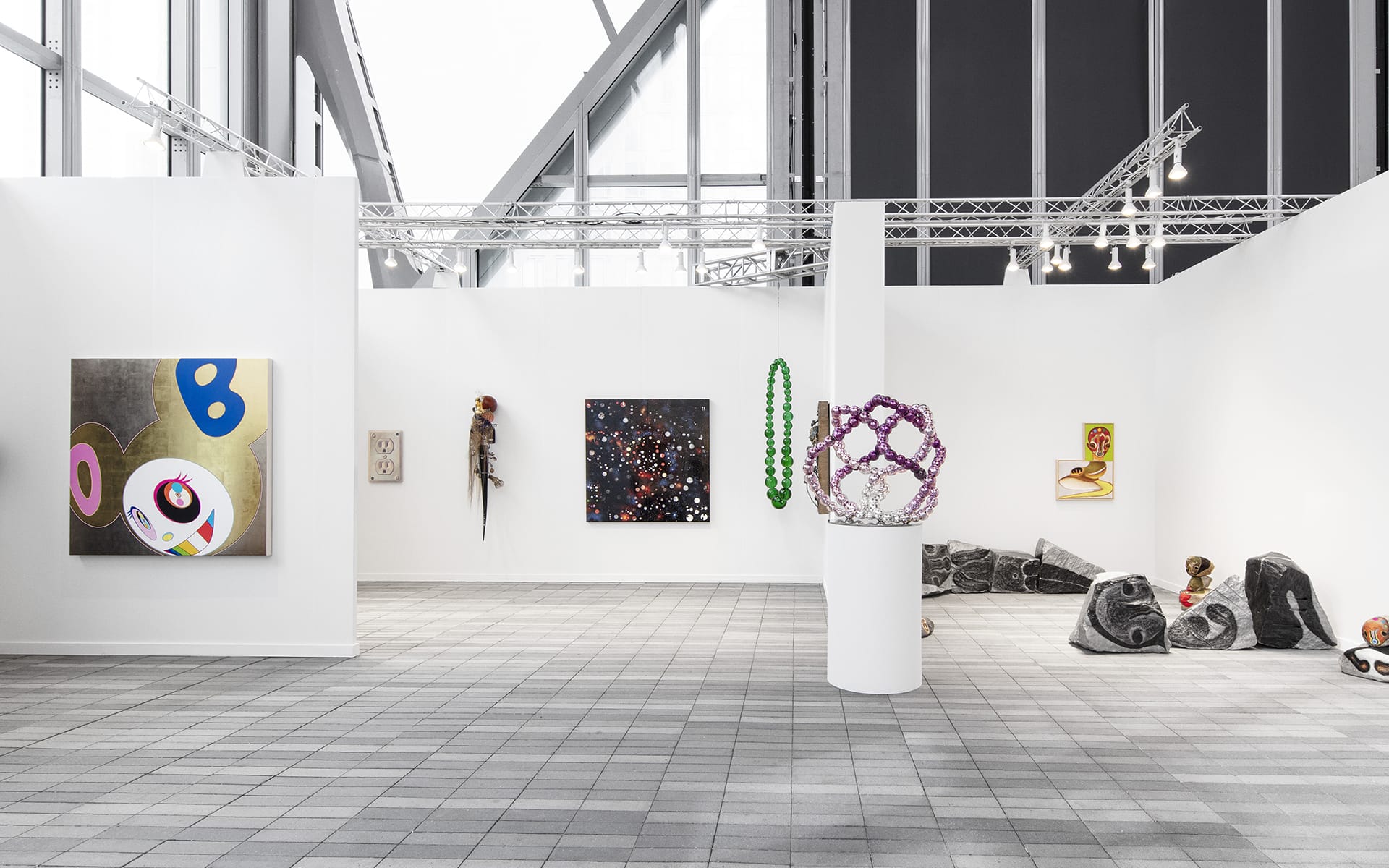 Art gallery interior with various modern artworks displayed on white walls and sculptures on the floor.