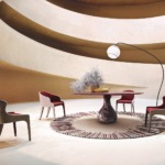 Modern dining room with round table, four chairs, abstract rug, tall lamp, and curved architectural ceiling design.