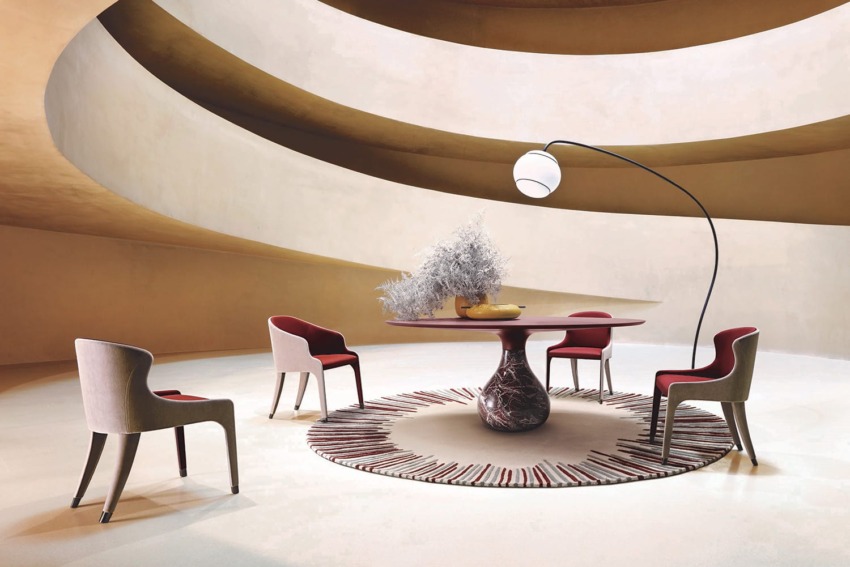 Modern dining room with round table, four chairs, abstract rug, tall lamp, and curved architectural ceiling design.