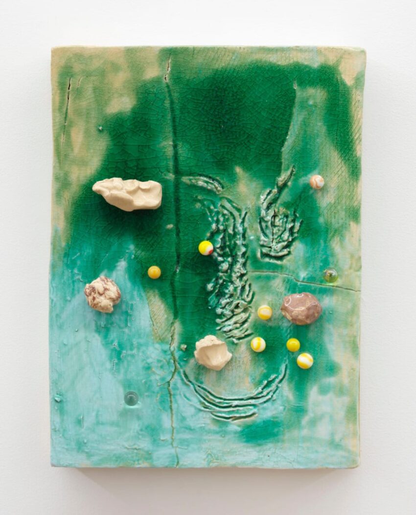 Abstract mixed media artwork with green textured background, featuring small objects and patterns resembling natural elements.