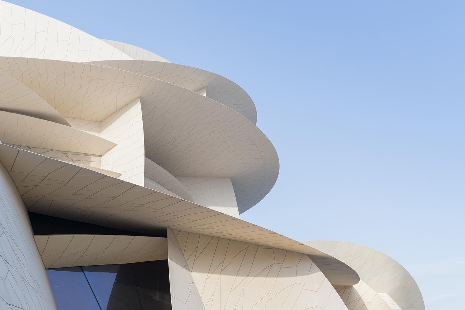 Modern architectural structure with large white overlapping discs against a clear blue sky.