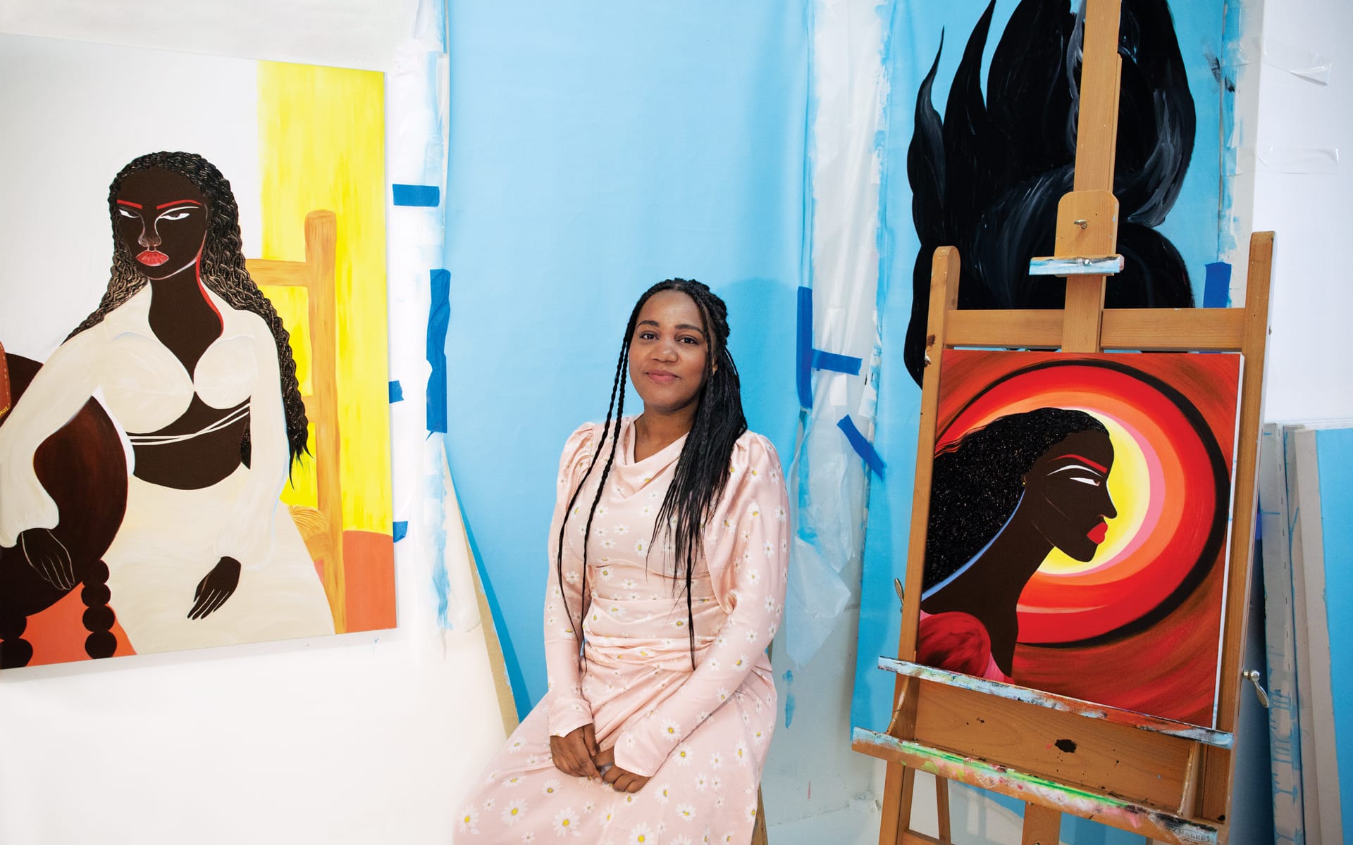 Artist seated in studio surrounded by vibrant paintings, featuring expressive portraits and dynamic color contrasts.