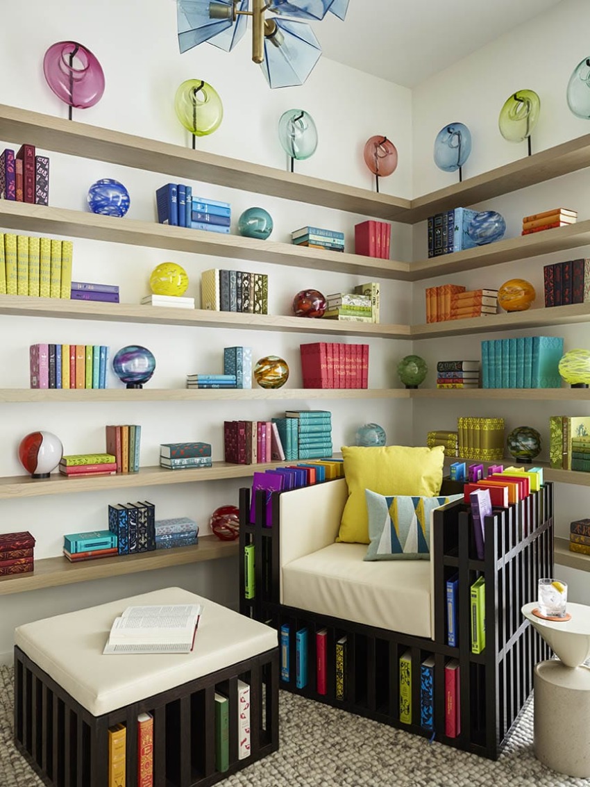 Colorful modern library with books, glass spheres, and a unique chair with cushions in a cozy reading nook.