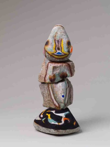 Stacked abstract sculpture with colorful patterns on stone-like material against a neutral background.