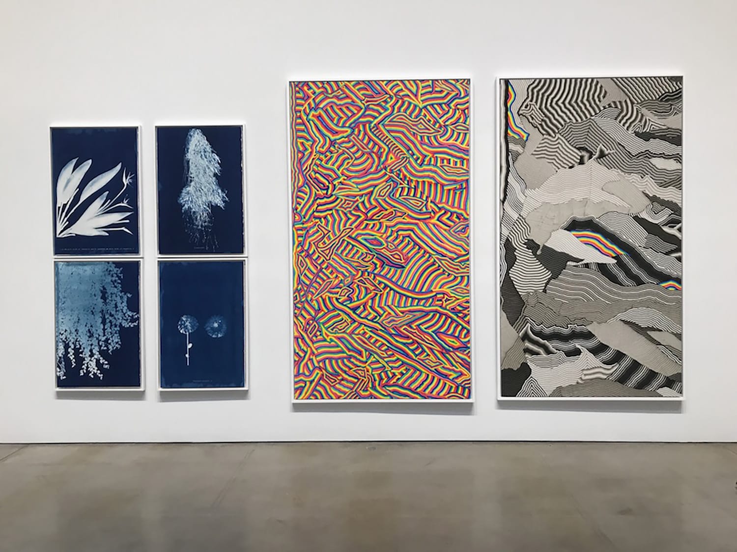 Exhibition display of six abstract artworks on a white wall, featuring various patterns and colors in a modern gallery setting.