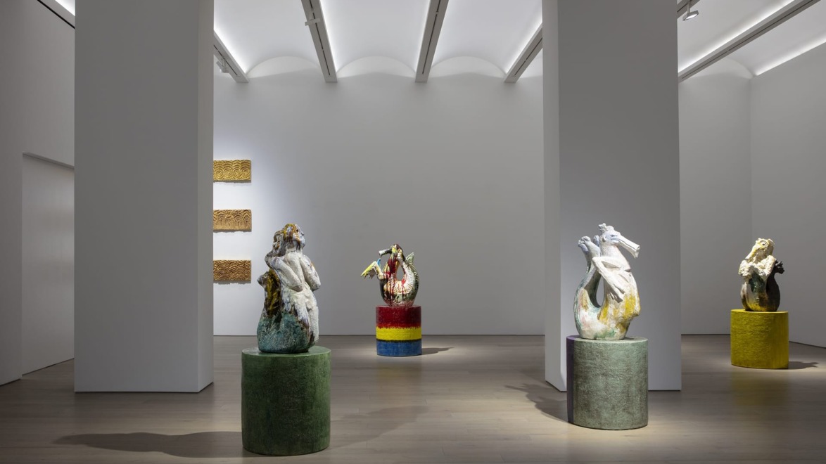 Contemporary art gallery with colorful sculptures and textured wall art under soft white lighting.
