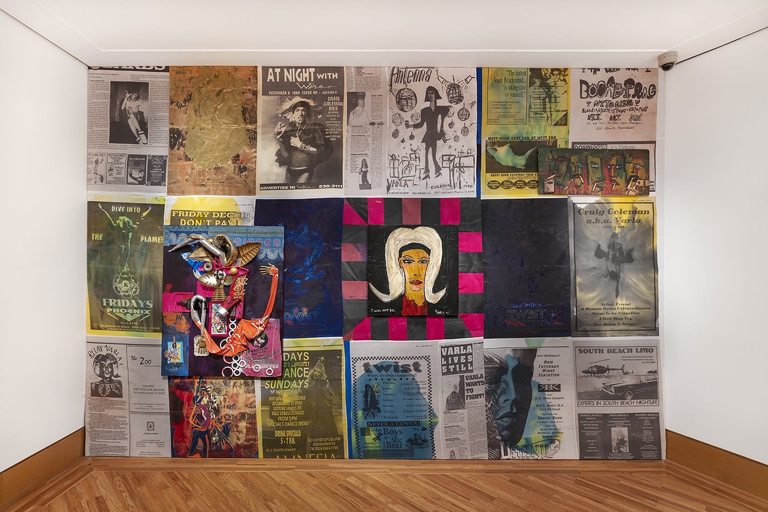 Collage of newspaper clippings, colorful artwork, and illustrations displayed on a gallery wall.