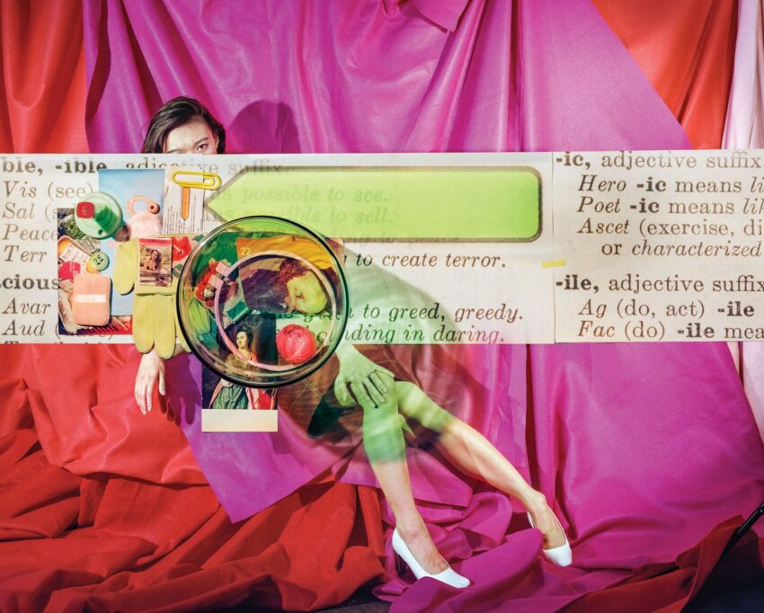 A person partially hidden behind a collage of household items and text against a vibrant red fabric background.