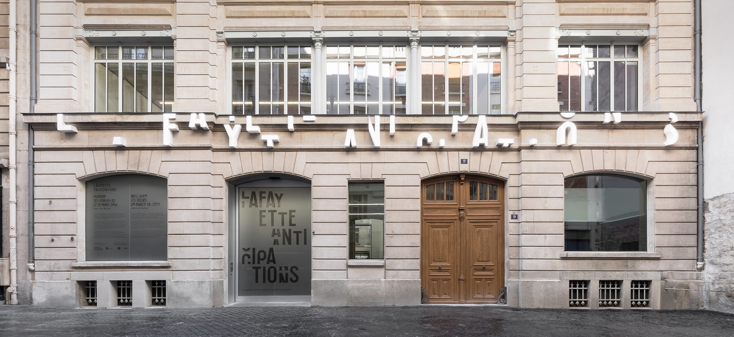 Facade of a historic building with a modern art installation featuring letters on the upper portion of the structure.