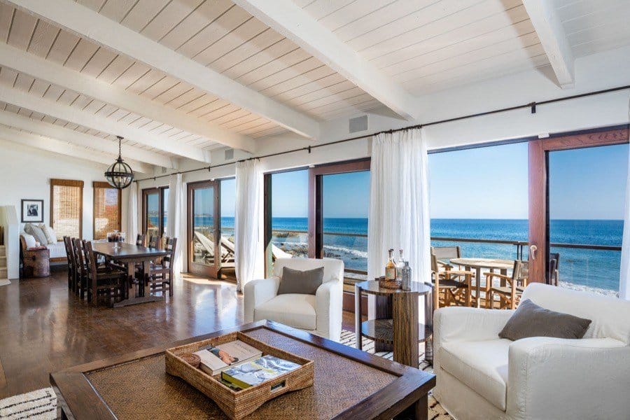 Spacious beachfront living room with large windows, ocean view, and elegant, cozy furniture.