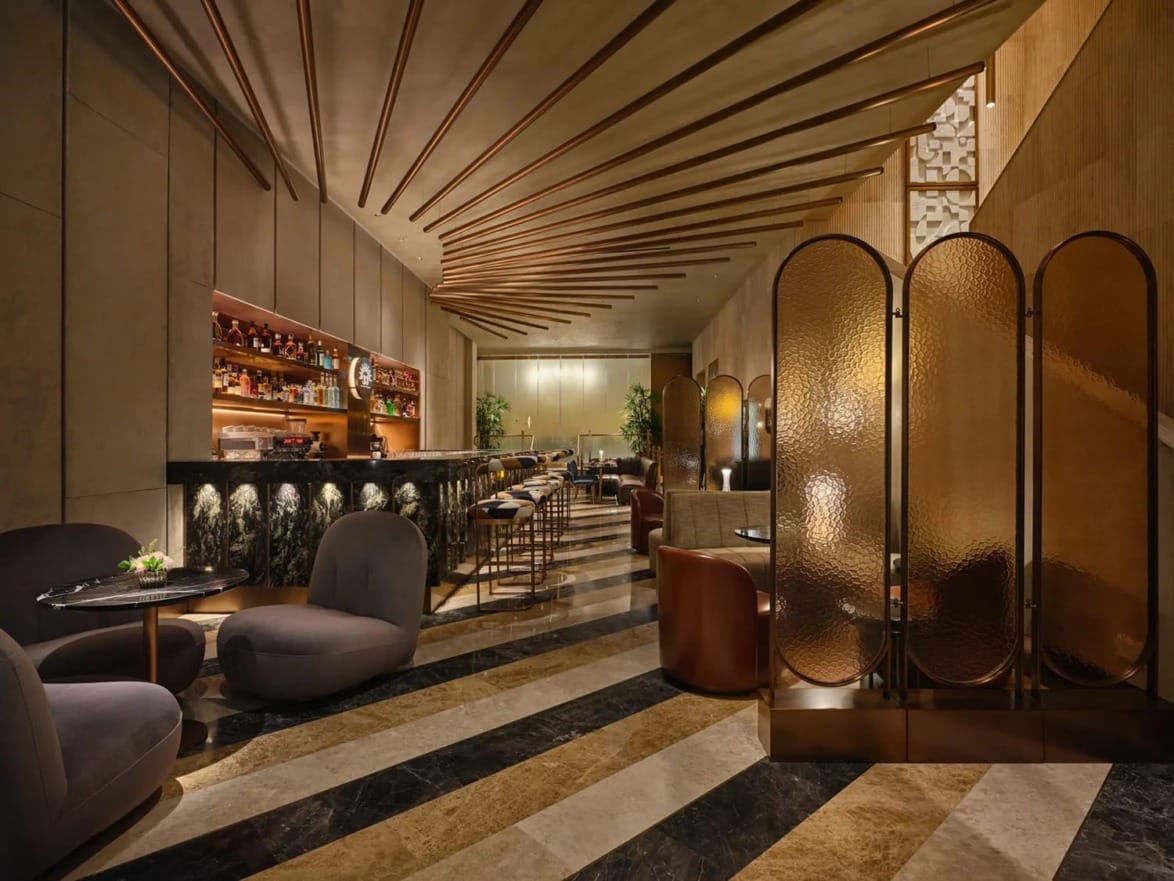 Stylish modern bar with cozy seating, a well-stocked bar, elegant lighting, and decorative partitions in a chic interior.