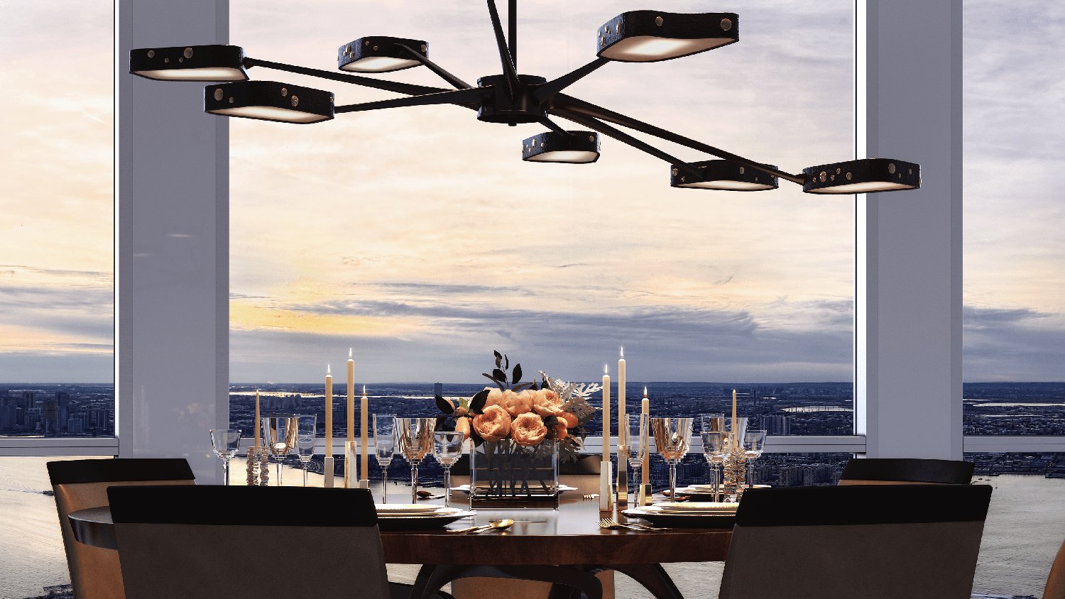 Elegant dining table set for dinner with flowers and candles, under a modern chandelier, with a cityscape view at sunset