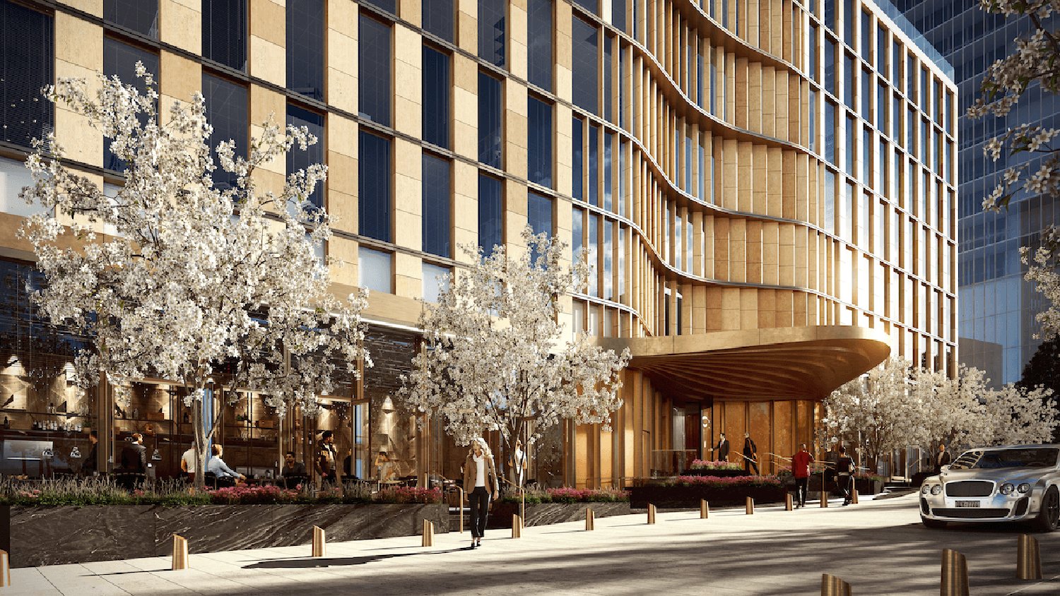 Modern building exterior with curved facade, large windows, and surrounding trees on a bright day.