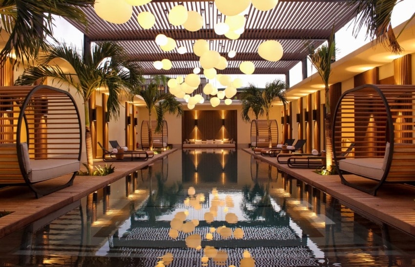 Luxurious pool area with modern loungers, hanging lanterns, and tropical plants creating a serene, inviting atmosphere.