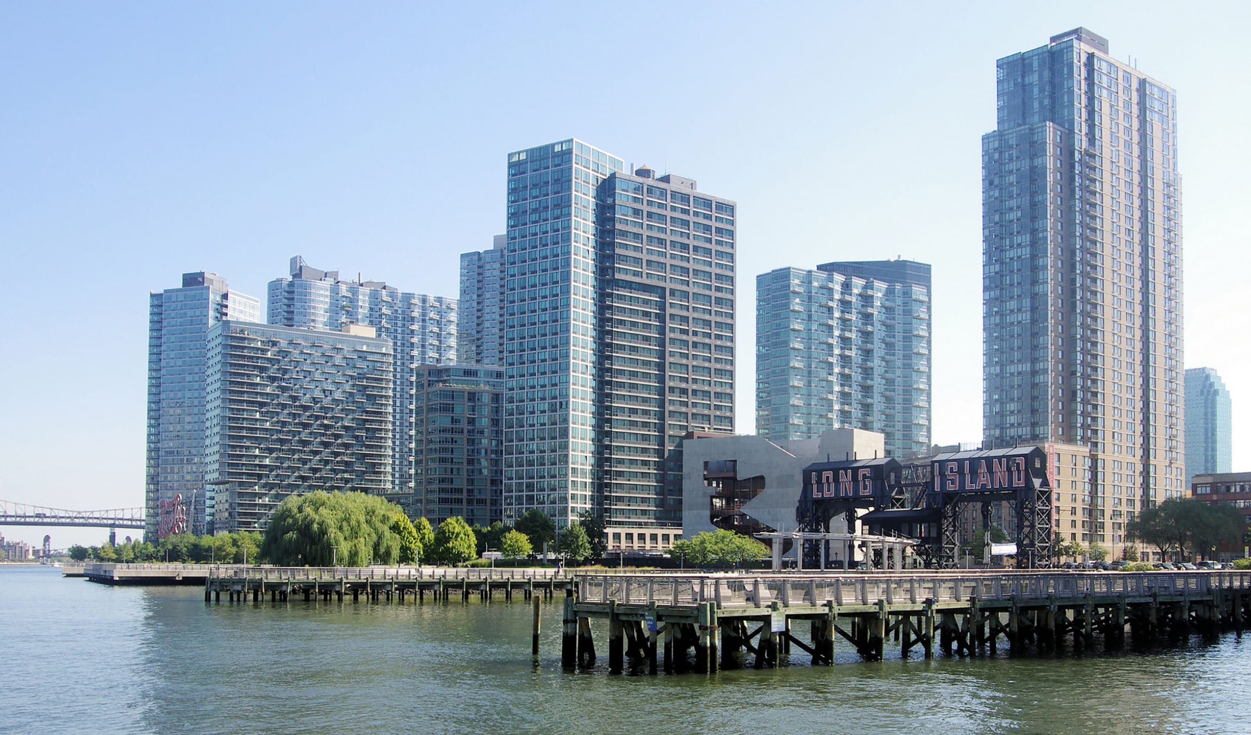 Skyline of Long Island City, New York, with modern high-rise buildings and waterfront view on a sunny day.