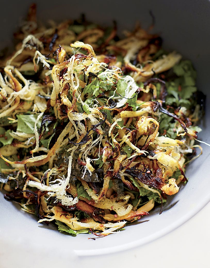 Crispy mixed vegetable salad with herbs and thinly sliced fried onions in a gray bowl.