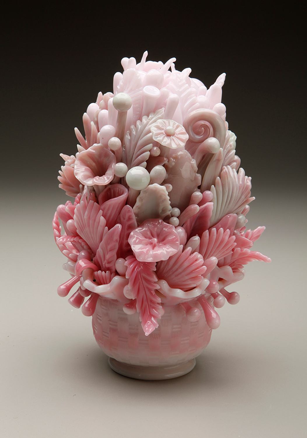 Pink and white intricate glass sculpture resembling flowers and leaves in a vase