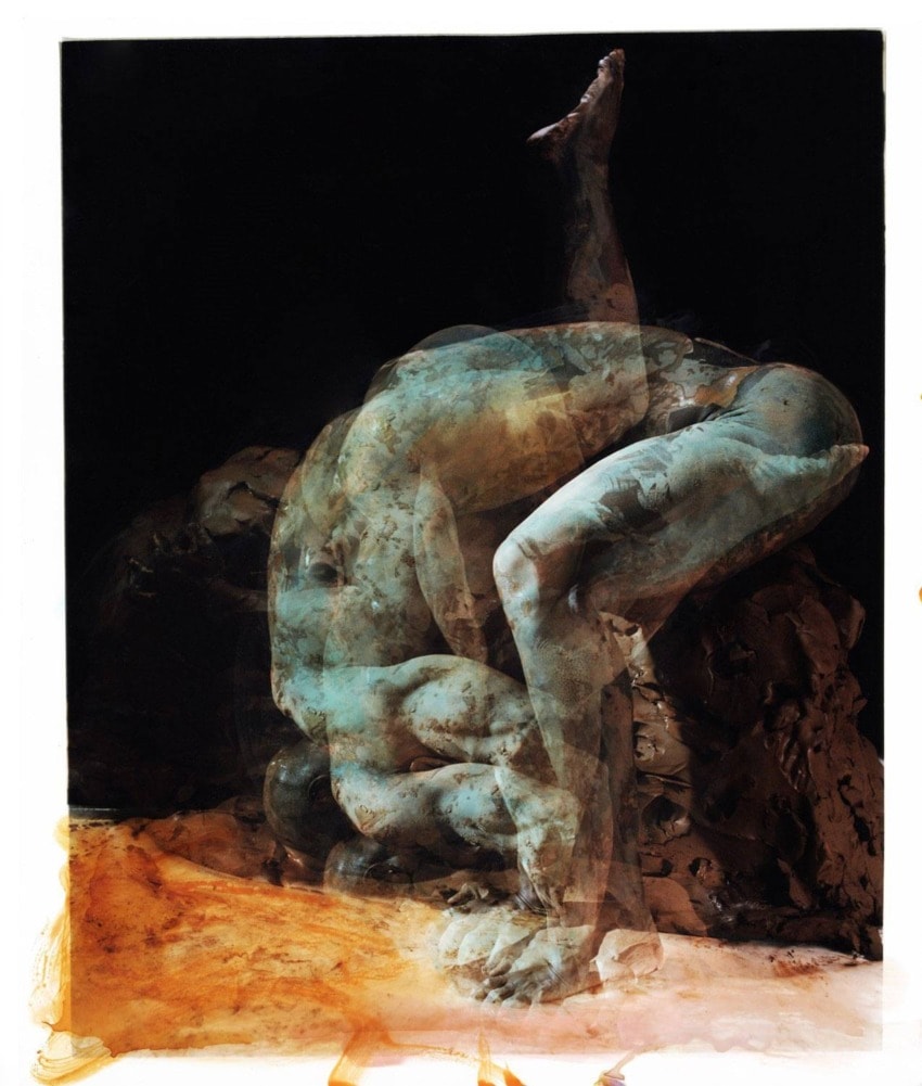 Abstract sculpture of a human figure in a dynamic pose, with layered textures and earthy tones on a dark background.