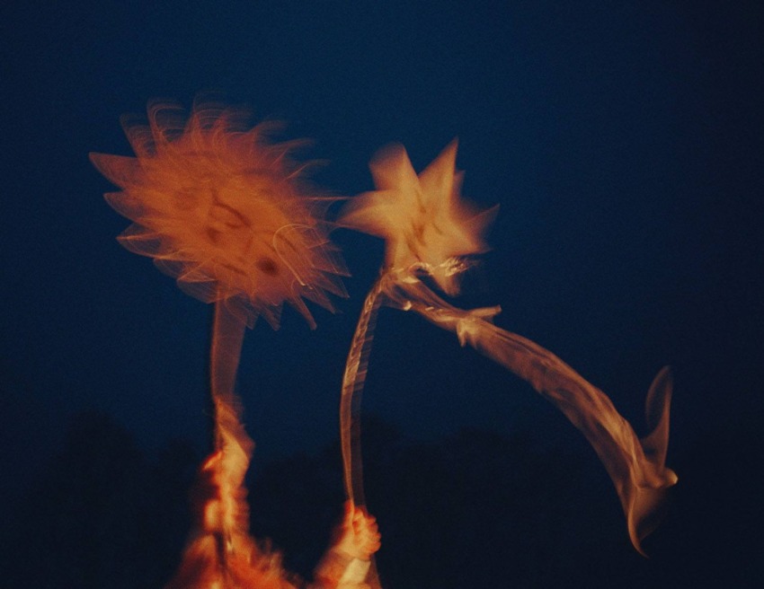 Abstract image of glowing orange shapes resembling suns or stars against a dark blue background.