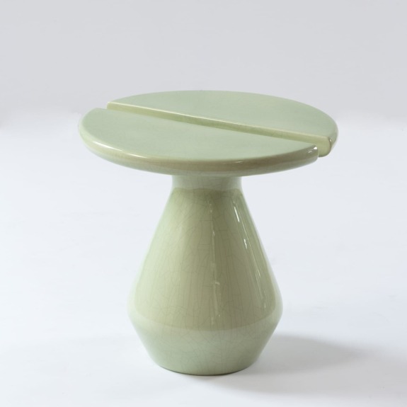 Green ceramic stool with a split circular top and smooth, glazed finish on a white background
