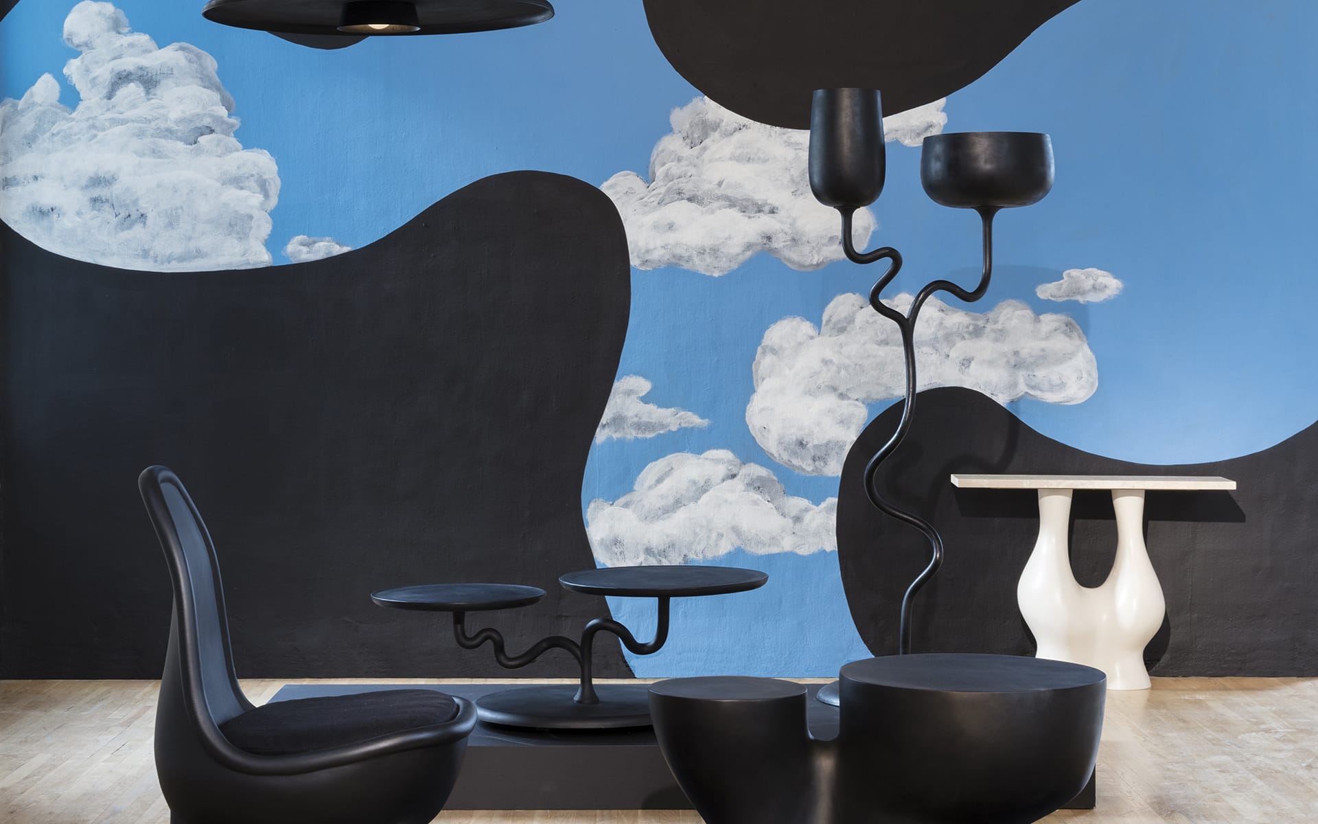 Modern art-inspired room with abstract black furniture and a blue wall featuring white cloud designs.