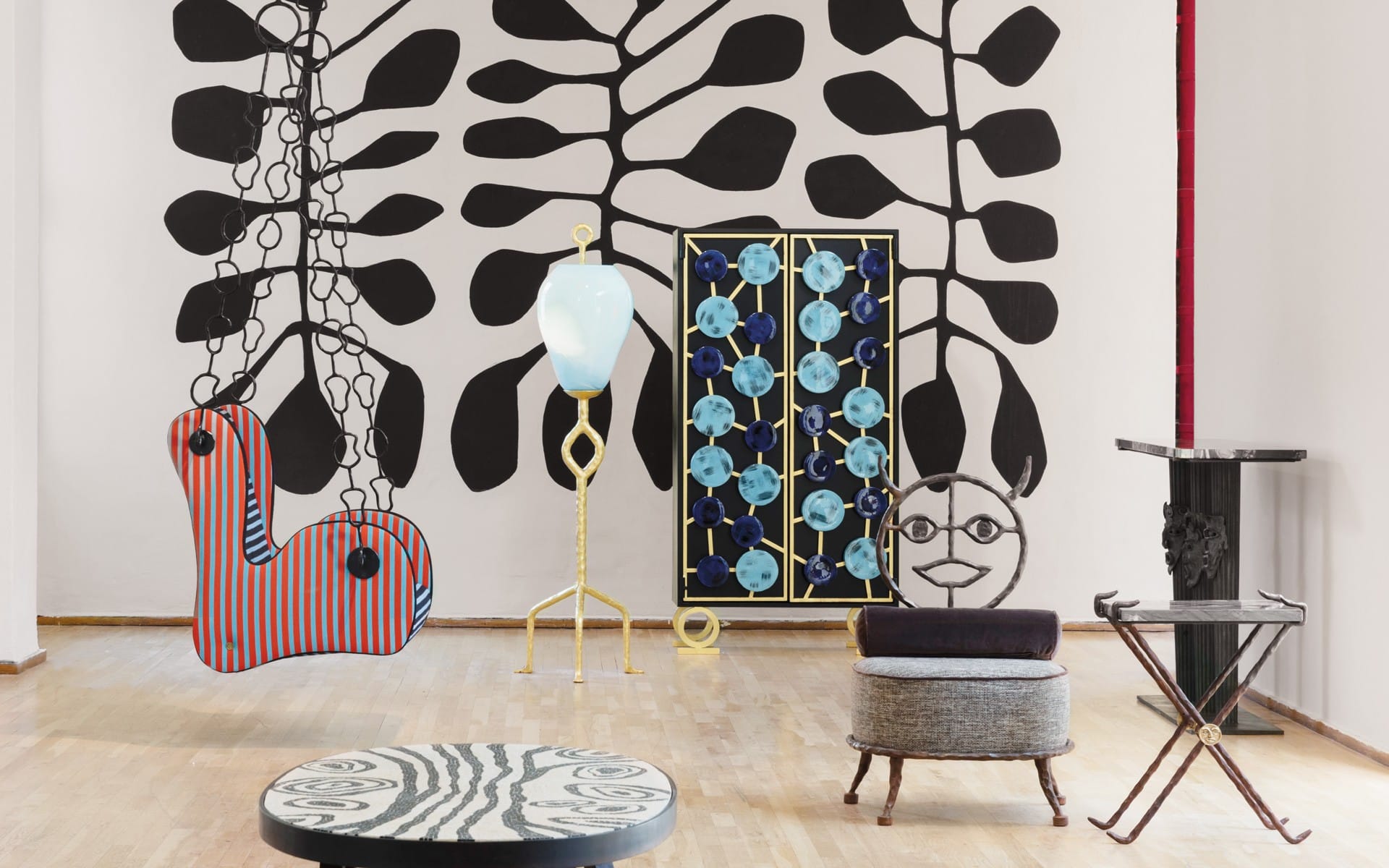 Eclectic art installation with abstract sculptures and colorful patterns in a modern gallery setting with wooden floors.