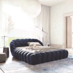 Modern bedroom with dark blue, tufted bed, stylish chair, abstract rug, large windows, and minimalist decor.