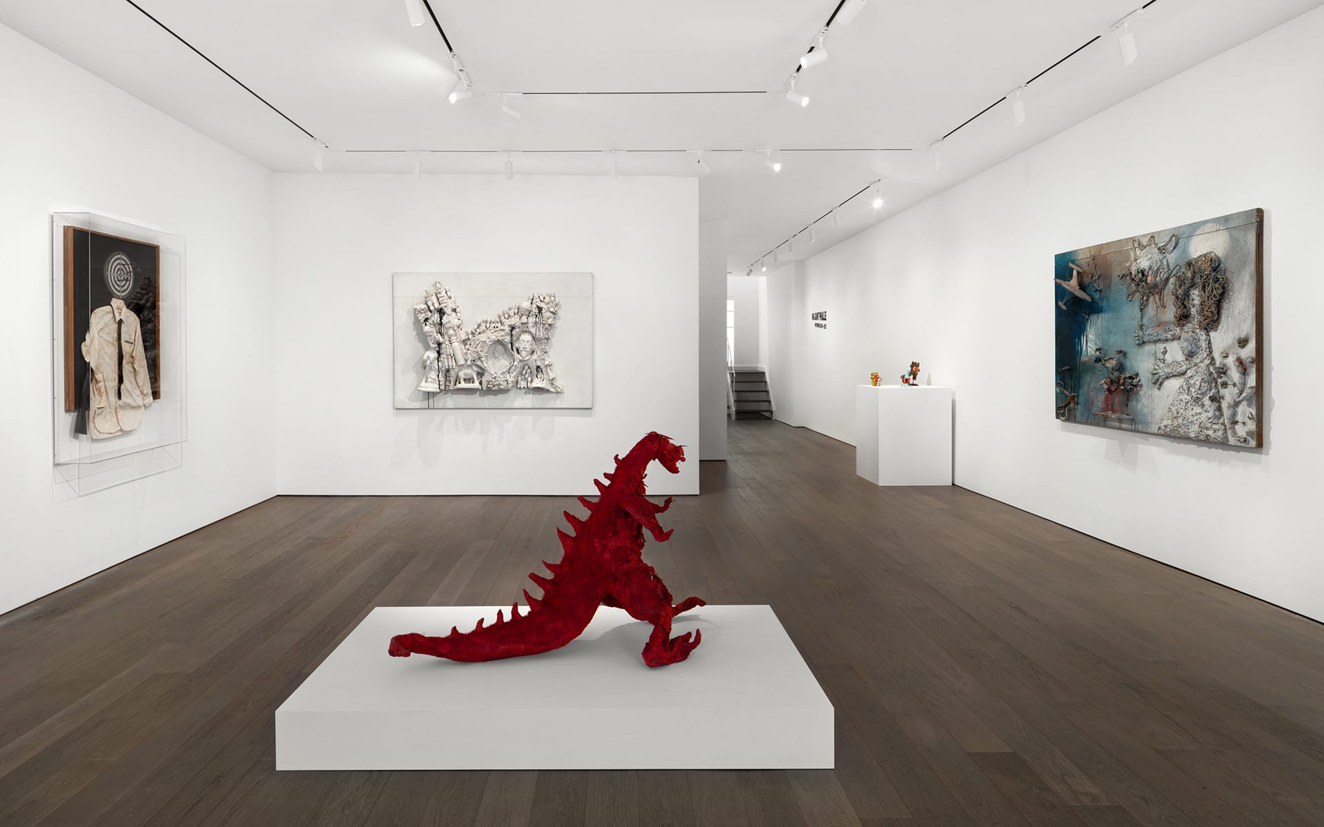 Contemporary art gallery with a red dinosaur sculpture on a white pedestal and abstract paintings on white walls.