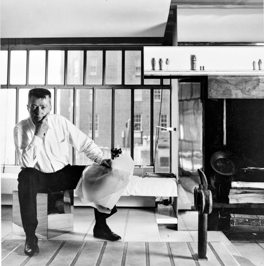 Man sitting in a modern room with a geometric design and reflective surfaces.